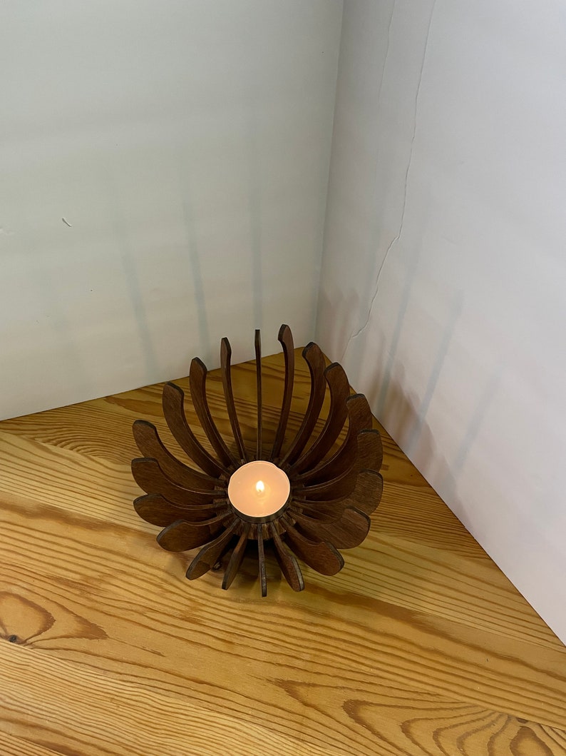 K&ouml;nnte beinhalten: Ein Kerzenhalter aus Holz in Form einer Blume mit einer brennenden Kerze in der Mitte.