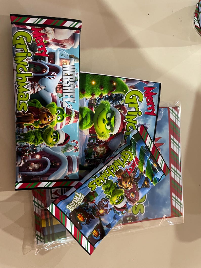 Może przedstawiać: Batony czekoladowe Hershey's i Rice Krispies Treats z opakowaniem w stylu Grincha. Opakowanie przedstawia Grincha, sceny z Whoville i słowa "Merry Grinchmas". Opakowania mają czerwone, białe i zielone akcenty.