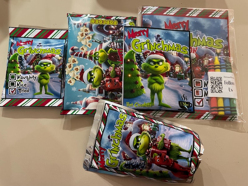 Może przedstawiać: Asortyment smakołyk&oacute;w i aktywności o tematyce Grinchmas. Zawiera popcorn, gorącą czekoladę i zestaw kredek. Opakowanie przedstawia postać Grincha, choinki i napis "Merry Grinchmas".