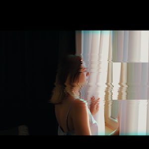 Puede incluir: Una mujer se encuentra de pie junto a una ventana, mirando hacia afuera. La ventana est&aacute; cubierta por una cortina blanca, y la luz del exterior crea un suave resplandor en el rostro de la mujer. La imagen tiene una est&eacute;tica vintage y de ensue&ntilde;o.