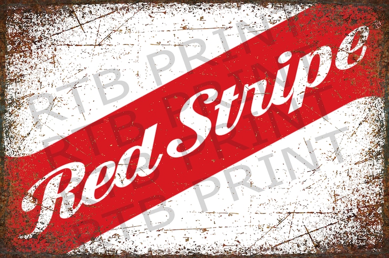 Op de afbeelding: Een vintage metalen bord met een diagonaal rood-wit gestreept ontwerp. De woorden "Red Stripe" zijn in wit op de rode streep gedrukt.