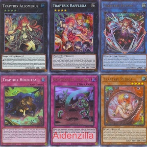 Puede incluir: Un conjunto de diez cartas coleccionables de juego de cartas coleccionables Yu-Gi-Oh! que representan ilustraciones de varios personajes del arquetipo "Traptrix". Las cartas tienen un acabado hologr&aacute;fico y presentan una variedad de colores, incluyendo verde, azul, rosa y morado.