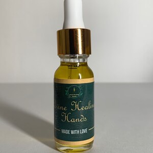 May include: A small, clear glass bottle with a gold lid and a white dropper. The bottle contains a yellow liquid and has a green label that reads "Divine Healing Hands" and "Made with Love".