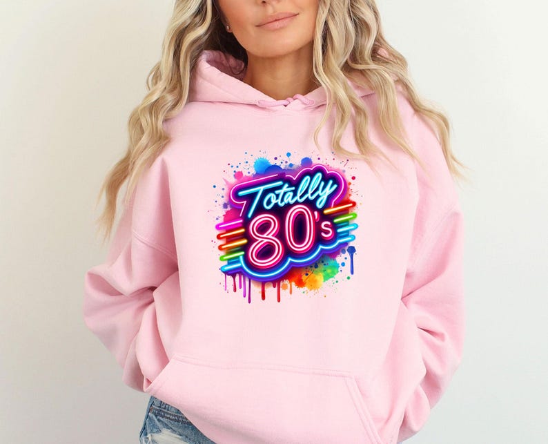 May include: Pink hoodie with a graphic print of a neon sign that says "Totally 80's" with rainbow colored paint splatters.