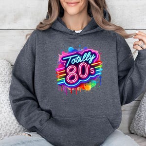 May include: A dark gray hoodie with a neon pink and blue graphic that says "Totally 80's" with a rainbow paint splatter effect.