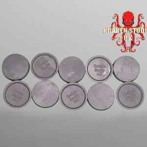 May include: Ten round, gray plastic bases with the text "Kraken Studio UK" printed on them.