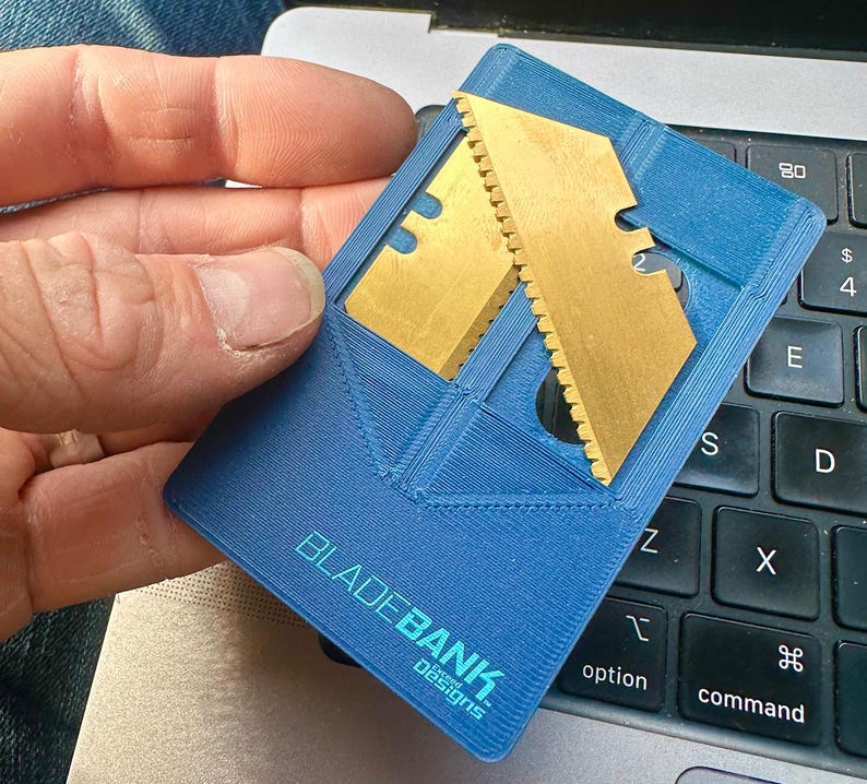May include: A blue plastic card with a gold metal blade insert. The card has the text "BLADEBANK" and "Concept Designs" printed on it.