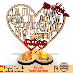 May include: A wooden heart-shaped candle holder with a romantic message in Spanish. The design includes two red heart cutouts with names, two lit candles, and a decorative arrow. The base is also heart-shaped.