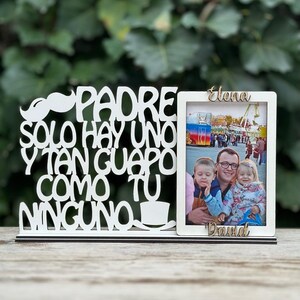 May include: White wooden picture frame with the text "Padre solo hay uno y tan guapo como tu ninguno" and a photo of a man with two children. The names "Elena" and "David" are written on the frame.