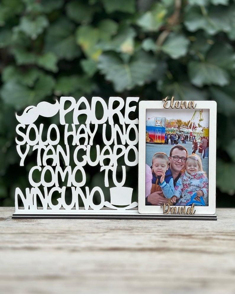 May include: White wooden picture frame with the text "Padre solo hay uno y tan guapo como tu ninguno" and a photo of a man with two children. The names "Elena" and "David" are written on the frame.
