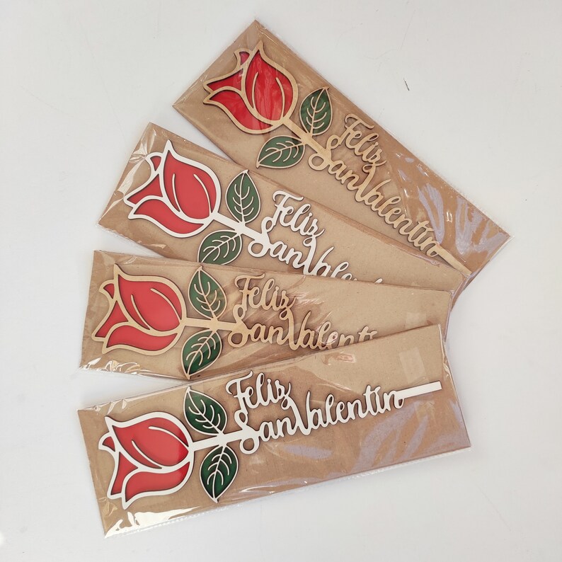 Puede incluir: Cinco tarjetas de papel marr&oacute;n con recortes de rosas de madera roja y verde y el texto "Feliz San Valent&iacute;n" en cada tarjeta.