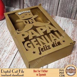 Może przedstawiać: Drewniana skrzynka z wyciętym wzorem, na kt&oacute;rym widnieje napis "Un Papa Genial Feliz Dia" po hiszpańsku. Skrzynka jest ozdobiona wąsem i kapeluszem z napisem "Manuel".
