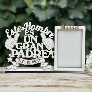 May include: White wooden picture frame with the text "Este Hombre Es Un Gran Padre Eres El Mejor" and a blank space for a photo. The name "Manuel" is written above the photo space.