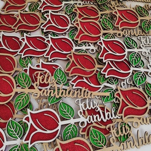 Puede incluir: Un mont&oacute;n de rosas rojas de madera con hojas de purpurina verde y el texto "Feliz San Valentin" en cada rosa.