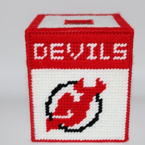 May include: A red, white, and black tissue box cover. The word "DEVILS" is displayed in white block letters on a red background. The team logo is also visible.