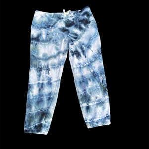 May include: Blue tie-dye sweatpants with a white drawstring. The sweatpants have a faded, abstract pattern.