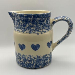May include: A blue and white ceramic pitcher with a speckled glaze and a row of blue hearts around the middle.