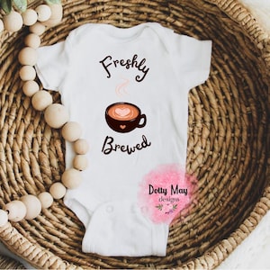 May include: White baby onesie with the text "Freshly Brewed" and a cartoon image of a coffee cup with steam coming from it.