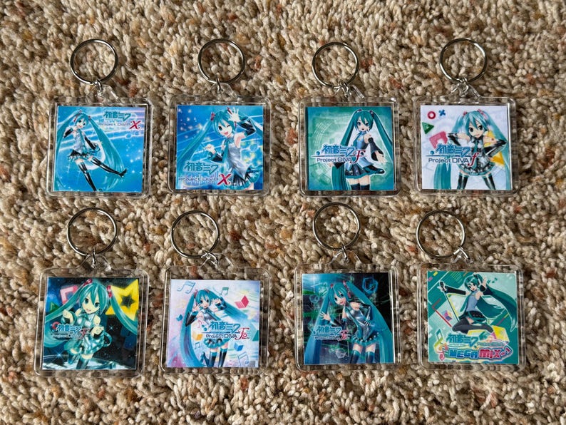 May include: Eight square acrylic keychains featuring Hatsune Miku in various poses and outfits. Each keychain includes a metal split ring and displays different colorful anime-style illustrations with Japanese text logos from the Project Diva series.