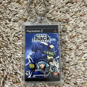 May include: Clear acrylic keychain featuring the cover art of the PlayStation 2 game .hack//Outbreak Part 3. The artwork includes a blue and white color scheme with Japanese text and the game's title. The keychain has a silver metal ring.