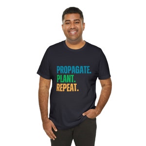 May include: A black t-shirt with the text "PROPAGATE. PLANT. REPEAT." in colorful, distressed lettering.