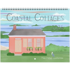 May include: A spiral-bound calendar featuring a coastal cottage illustration. The calendar cover displays a pink cottage with a gray roof, set against a backdrop of a blue sea and sky. Text includes "Coastal Cottages 2026" and "Mary McRae Illustration."