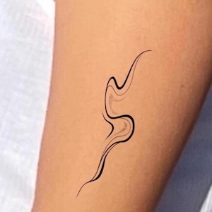 Op de afbeelding: Een minimalistisch zwart-wit lijnkunst tattoo ontwerp met een vloeiende, abstracte vorm. Het ontwerp heeft een gebogen, golvende vorm met een gestippelde sectie, aangebracht op de huid. Het is een eenvoudige, elegante lichaamskunst.
