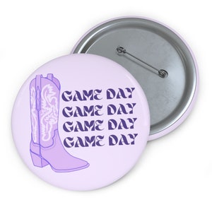 Puede incluir: Bota vaquera morada y blanca con el texto "GAME DAY" repetido cuatro veces sobre un fondo lavanda.