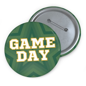 May include: A green button with a white star pattern and the text "GAME DAY" in white letters with a gold outline.