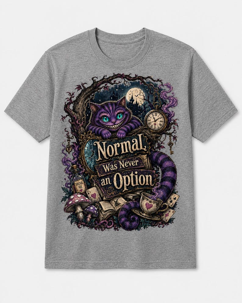 May include: A heather gray short-sleeve t-shirt featuring a graphic print of a purple striped cat, a pocket watch, mushrooms, and playing cards. The text "Normal Was Never an Option" is centered in the design with dark, whimsical forest elements.