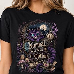 May include: A black short-sleeved t-shirt featuring a graphic print of a purple striped cat with glowing teal eyes. The design includes a pocket watch, a bottle labeled Drink Me, mushrooms, and the text Normal Was Never an Option.