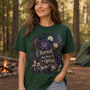 May include: A dark green short-sleeve t-shirt featuring a graphic print of a purple grinning cat, a pocket watch, mushrooms, and playing cards. The text on the shirt reads, "Normal Was Never an Option," surrounded by swirling purple smoke and tree branches.