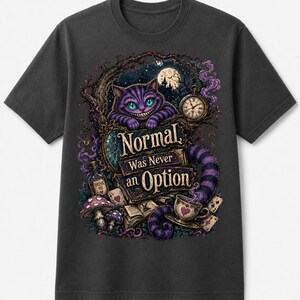 May include: A charcoal gray t-shirt featuring a graphic print of a purple striped cat with a wide grin, a pocket watch, a teacup, mushrooms, and playing cards. The text "Normal Was Never an Option" is printed in the center of the detailed illustration.