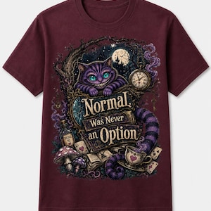 May include: A maroon short-sleeve t-shirt featuring a graphic print of a purple striped cat with a wide grin, a pocket watch, a teacup, mushrooms, and playing cards. The text reads, "Normal Was Never an Option" in a stylized, decorative font.