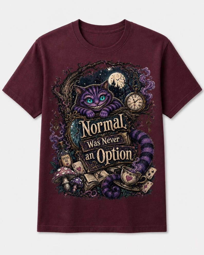 May include: A maroon short-sleeve t-shirt featuring a graphic print of a purple striped cat with a wide grin, a pocket watch, a teacup, mushrooms, and playing cards. The text reads, "Normal Was Never an Option" in a stylized, decorative font.