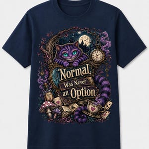 May include: A navy blue t-shirt featuring a graphic print of a purple striped cat with glowing eyes, a pocket watch, mushrooms, playing cards, and a bottle labeled Drink Me. The text reads Normal Was Never an Option in a decorative font.