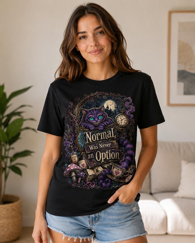 May include: A black short-sleeve t-shirt featuring a graphic print of a purple grinning cat, a pocket watch, a teacup, and mushrooms. The text reads, "Normal Was Never an Option," surrounded by intricate, dark, and whimsical fantasy-themed illustrations.
