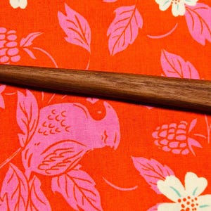 May include: A dark brown wooden hair stick with a curved end. The stick has the words "Made in Seattle" and "Field & Stream" engraved on it.