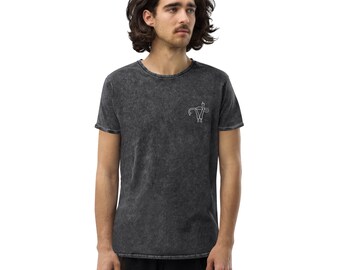 May include: Dark grey t-shirt featuring a white graphic of a uterus and the letters "W" and "K". The shirt has a crew neck and short sleeves. The fabric has a washed, vintage appearance.
