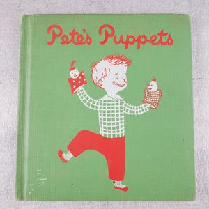May include: A vintage children's book titled "Pete's Puppets" with a green cover. The cover features a red-haired boy in a checkered shirt and red pants, holding two puppet hand-puppets. The title is in red script.