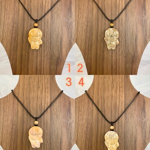 May include: Four necklaces with a wooden pendant in the shape of a cartoon character. The necklaces have black cords and the pendants are a light brown colour.