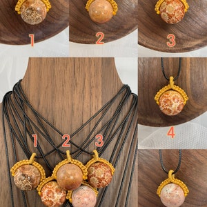 Puede incluir: Cinco collares con diferentes estilos de colgantes de coral. Cada collar tiene un cord&oacute;n negro y un nudo de macram&eacute; dorado alrededor del colgante de coral. Los colgantes de coral son todos de diferentes tonos de marr&oacute;n y naranja.