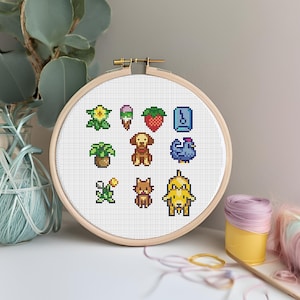 May include: A cross-stitch embroidery hoop with a white background and colourful pixelated images of a flower, ice cream, strawberry, a musical note, a plant, a dog, a chicken, a flower, a cat, and a dog.