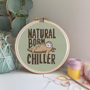 May include: A green embroidery hoop with a brown sloth design and the text "NATURAL BORN CHILLER".