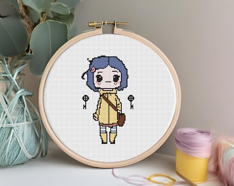 May include: A cross-stitch embroidery hoop featuring a pixelated cartoon character with blue hair, a yellow coat, and a brown satchel. Two black keys flank the character. The embroidery is set in a wooden hoop.