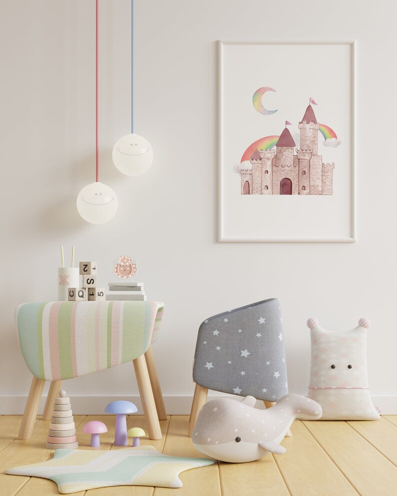 May include: A framed watercolour print of a castle with a rainbow and moon hangs on a white wall. A child's room is furnished with a striped table, a star-patterned chair, and a whale-shaped pillow. Decorative lamps hang from the ceiling.