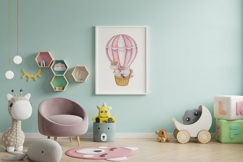 May include: A framed watercolour print of a unicorn in a hot air balloon, with pink and white stripes. The nursery decor includes a pink chair, stuffed animals, and wooden toys, creating a whimsical atmosphere.