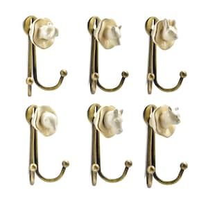 Könnte beinhalten: Sechs dekorative Wandhaken mit Tierkopfmotiven. Jeder Haken hat einen cremefarbenen Tierkopf, darunter ein Bär, ein Nashorn und ein Elefant, der auf einem messingfarbenen Metallhaken befestigt ist. Die Haken sind zum Aufhängen von Gegenständen gedacht.