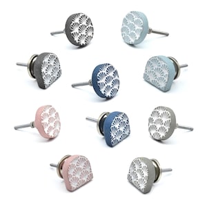 Puede incluir: Una colección de diez tiradores decorativos para armarios en varios colores, incluyendo gris, azul y rosa. Cada tirador presenta un diseño en forma de abanico en blanco. Los tiradores son redondos y semicirculares, con tornillos metálicos.