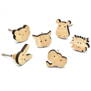 Könnte beinhalten: Eine Auswahl an Holzschrankknöpfen in Tierformen, darunter ein Bär, eine Eule, ein Nilpferd, ein Igel, ein Kaninchen und ein Elefant. Jeder Knopf hat eine helle Holzmaserung mit dunkelbraunen Akzenten und einen Metallstift.